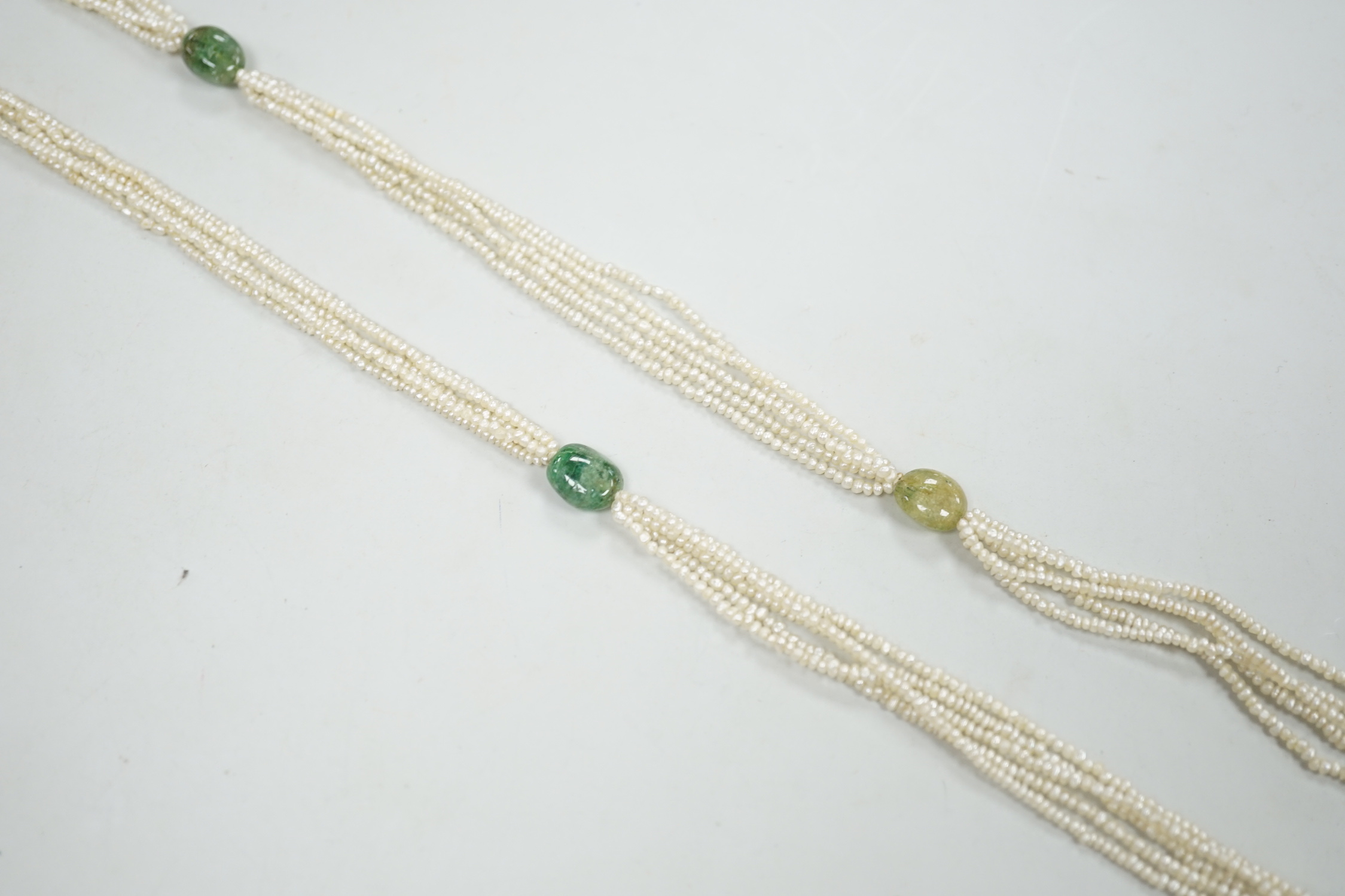 A 19th century Indian multi strand seed pearl and emerald? set long necklace, with gem set tassel drops, 176cm.